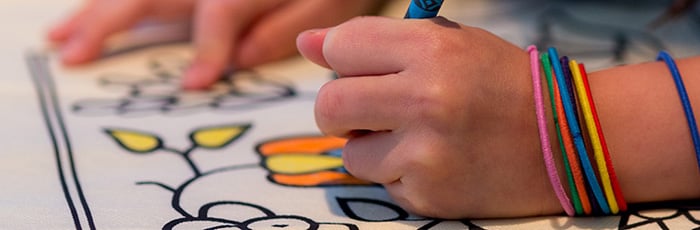 Child's hands coloring on a handbag.