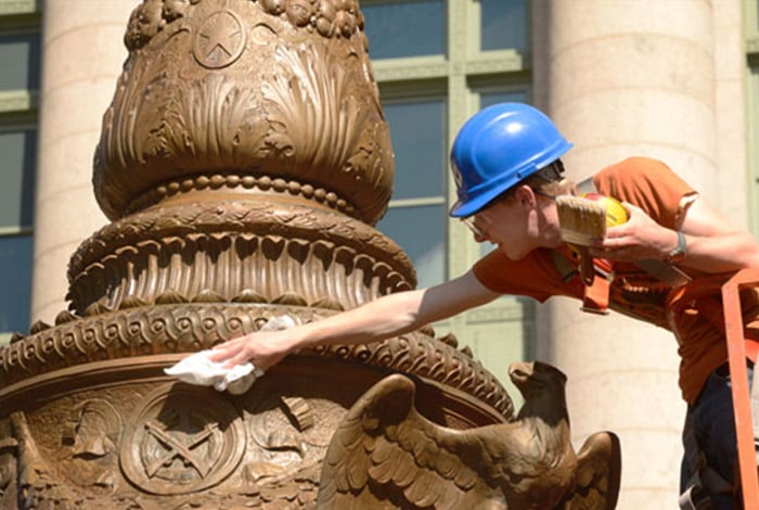 Conservator working the finsh of patina on a monument 